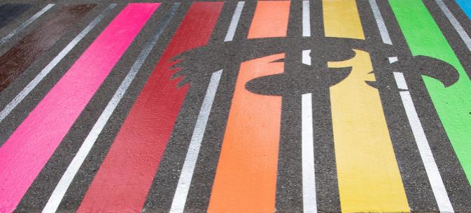 Rainbow-colored crosswalk painted on the pavement, with a Tigerhawk overlay